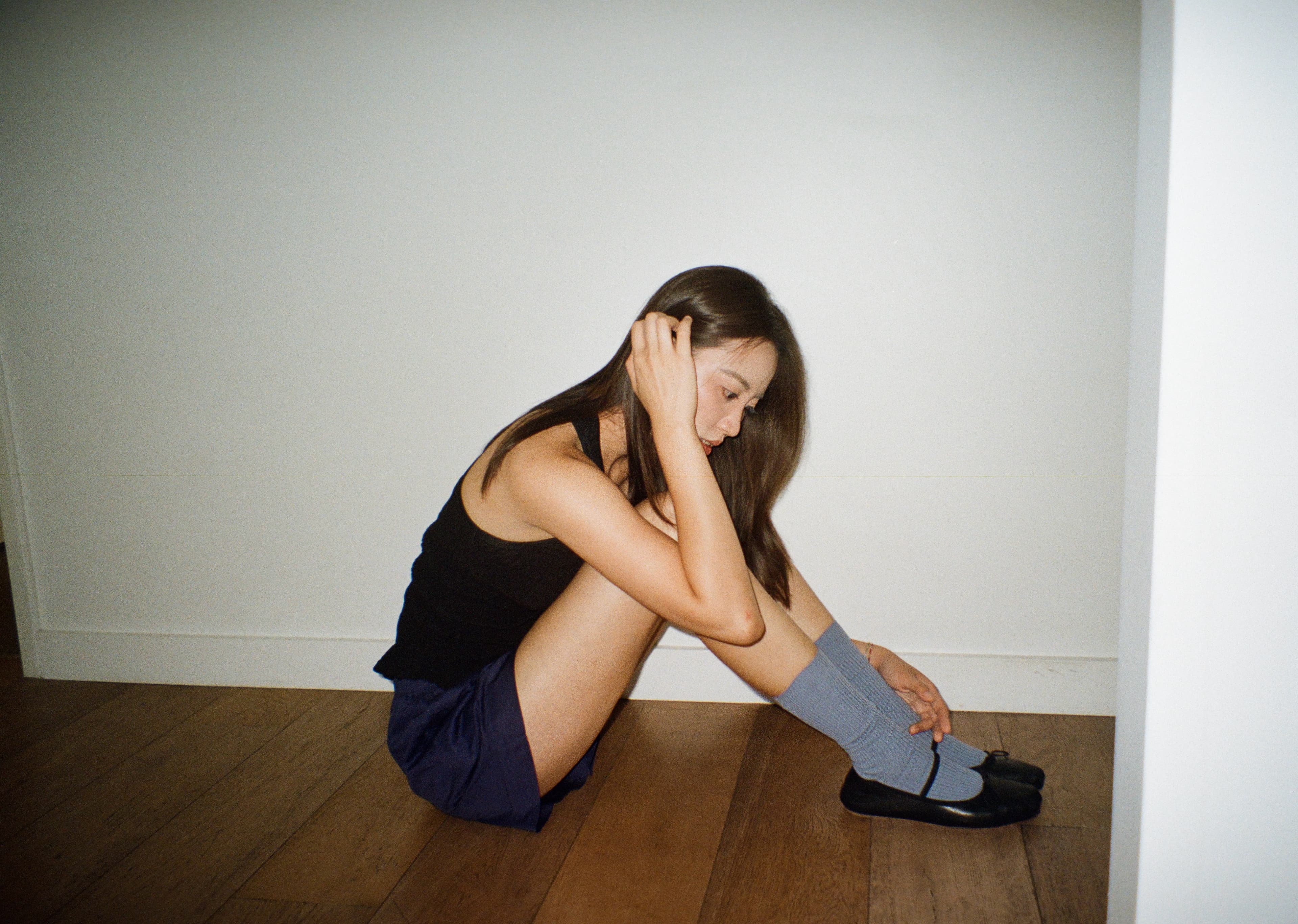 A film photograph of Eryou sitting on a wooden floor